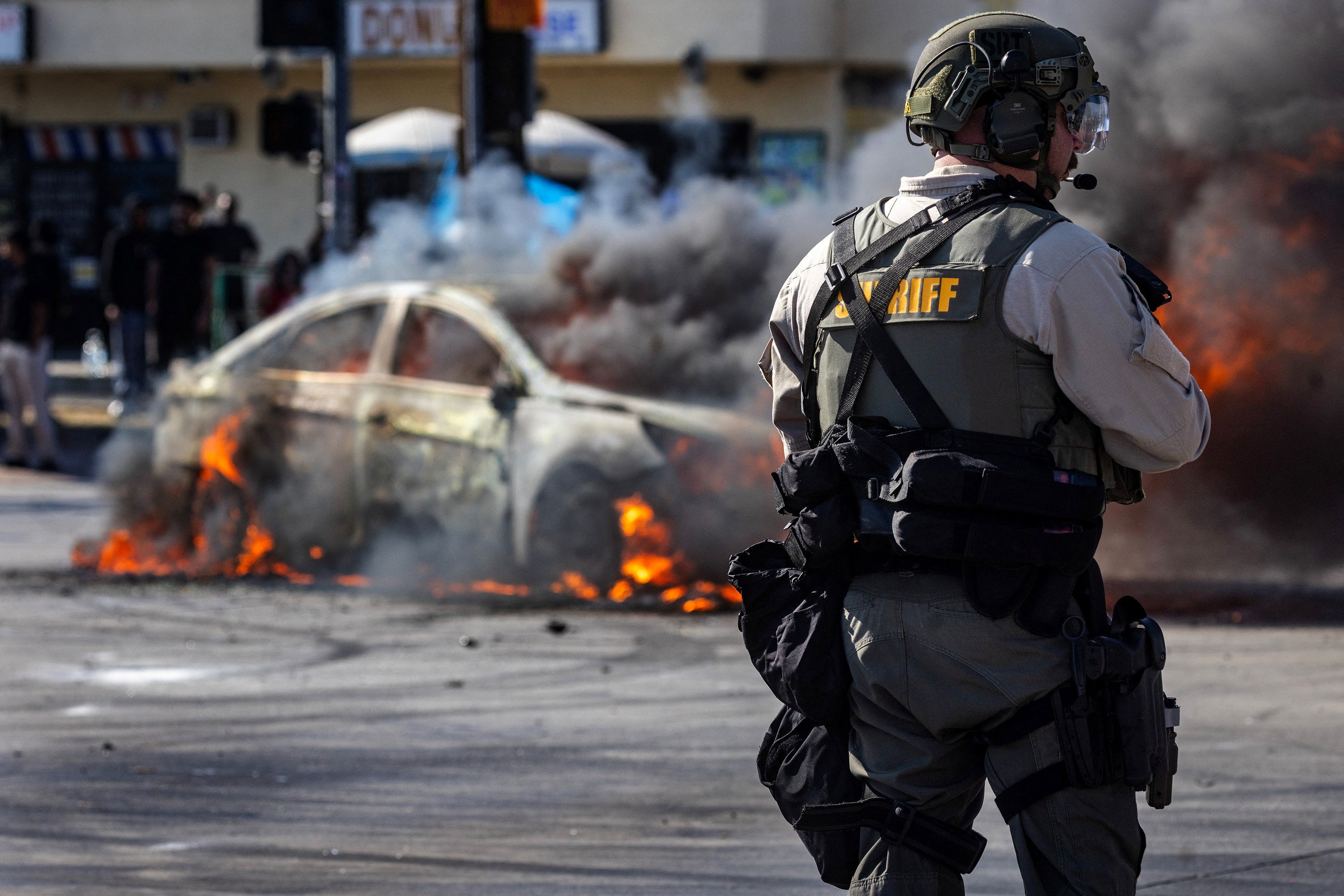 Smoke rises from a burning car on Atlantic Boulevard, Los Angeles, on Saturday during a standoff by protesters and law enforcement following raids by ICE agents